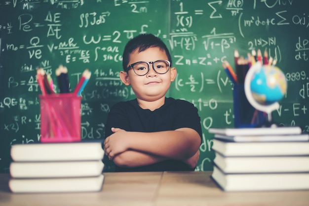 Menino pensativo com livro perto de um conselho escolar