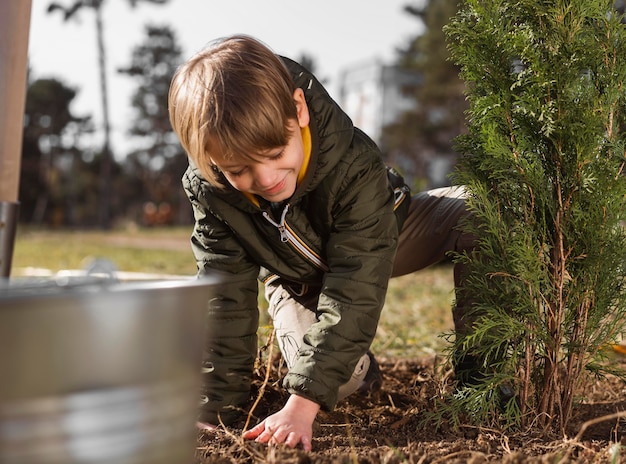 Foto grátis menino plantando uma árvore do lado de fora