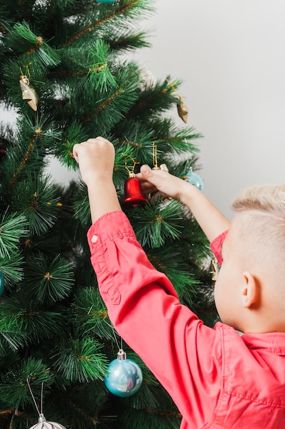 Menino que decora a árvore de natal