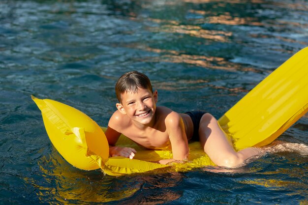 Menino se divertindo na piscina com boia