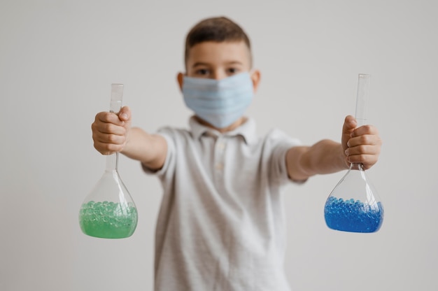 Foto grátis menino segurando elementos químicos em recipientes