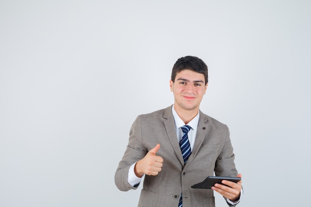 Menino segurando uma calculadora, mostrando o polegar em um terno formal