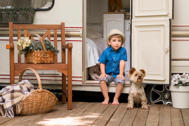 Menino sentado em uma caravana ao lado de um cachorro fofo