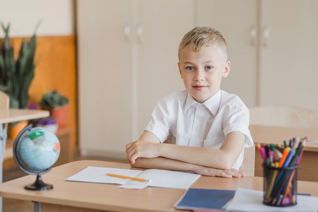 Foto grátis menino, sentando, com, mãos, tabela, em, sala aula