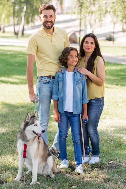 Foto grátis menino sorridente com cachorro posando com os pais enquanto estão no parque