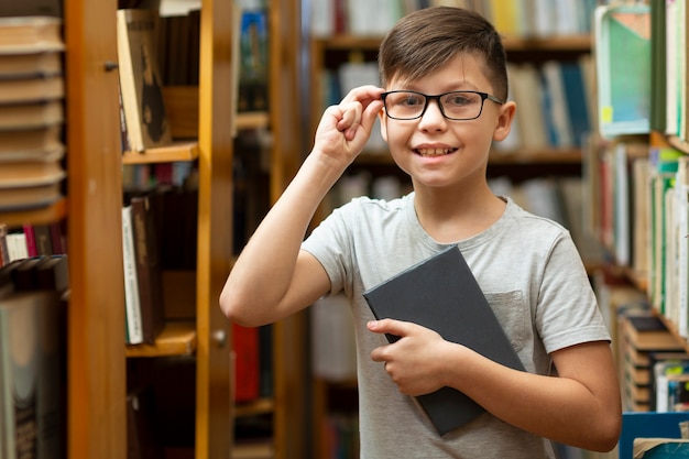Menino sorridente com óculos na biblioteca