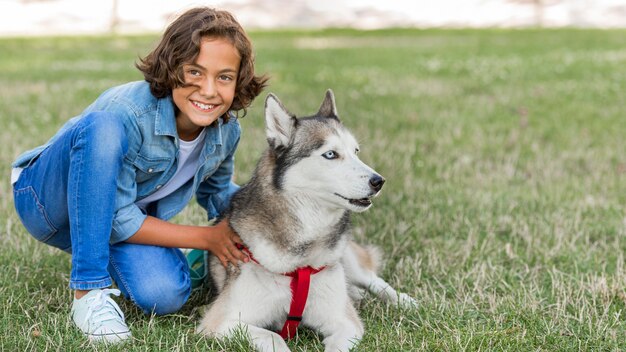 Menino sorridente posando com um cachorro enquanto está no parque