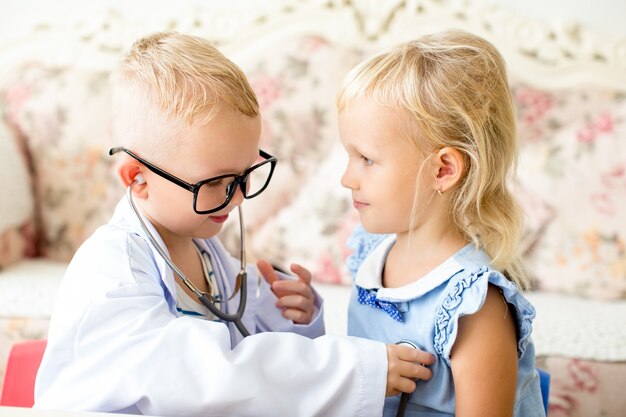 Menino sorridente que joga médico com namorada