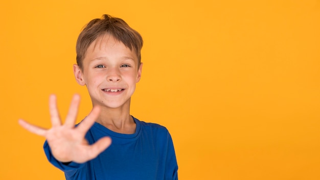 Menino sorridente segurando a mão para a frente com espaço de cópia