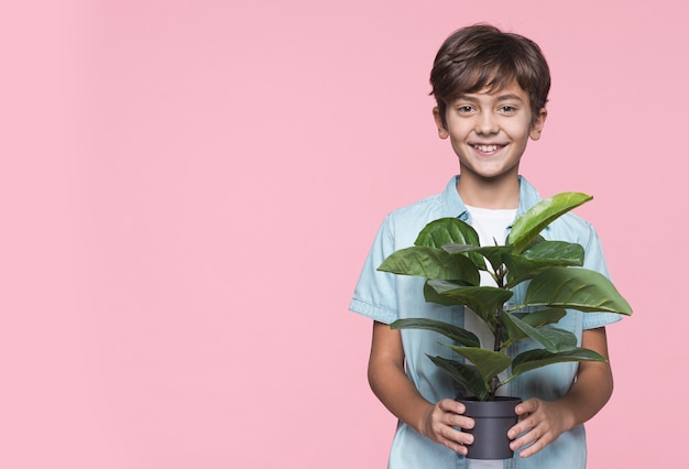 Menino sorridente segurando o vaso de flores