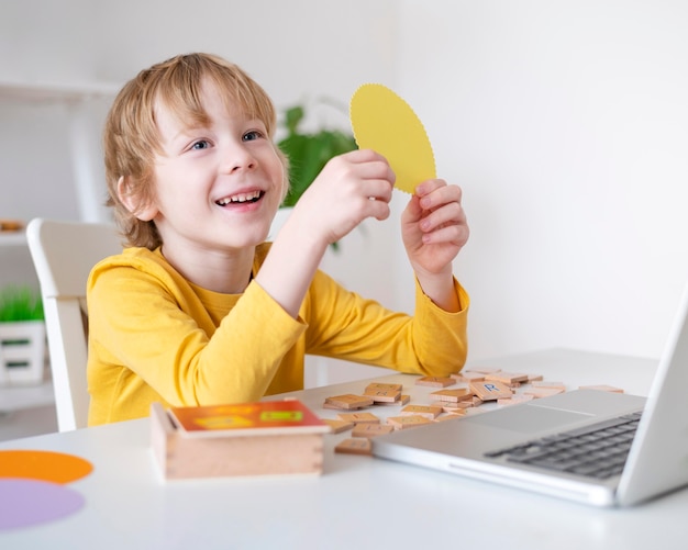 Menino sorridente usando laptop em casa