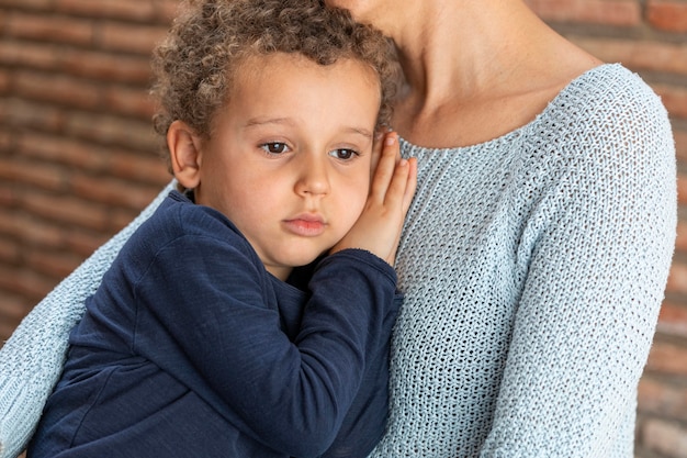 Menino triste consolado pela mãe