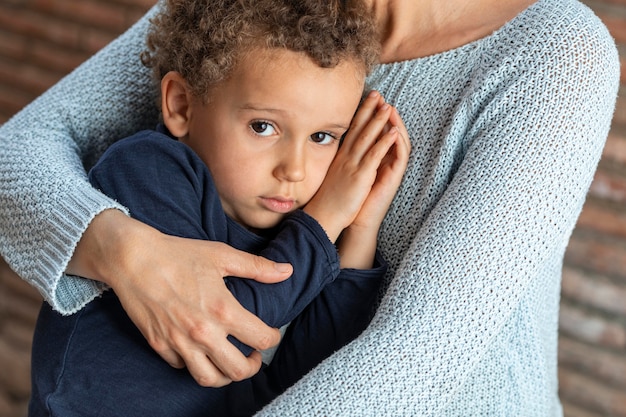 Menino triste consolado pela mãe