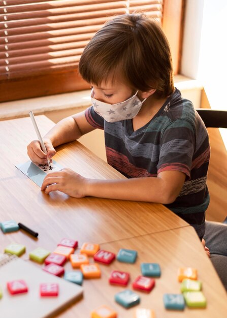 Menino usando máscara médica em suas aulas online