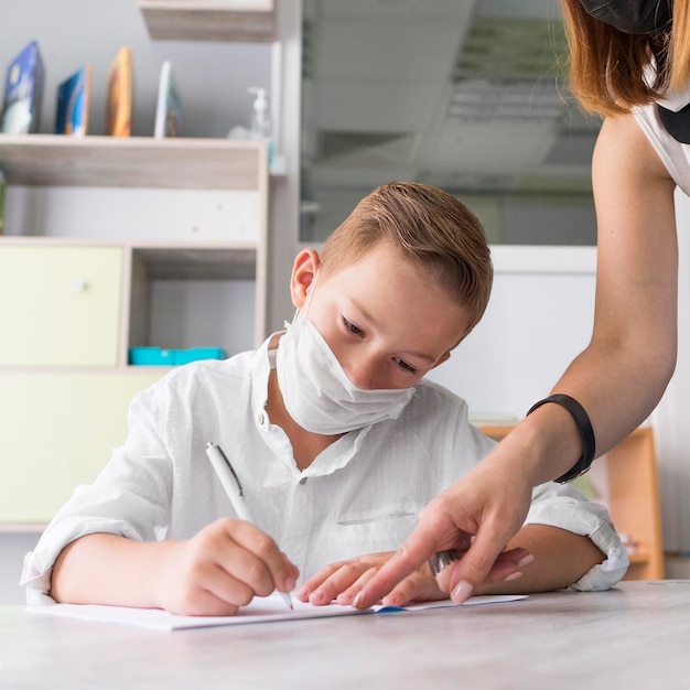 Menino usando uma máscara médica na sala de aula