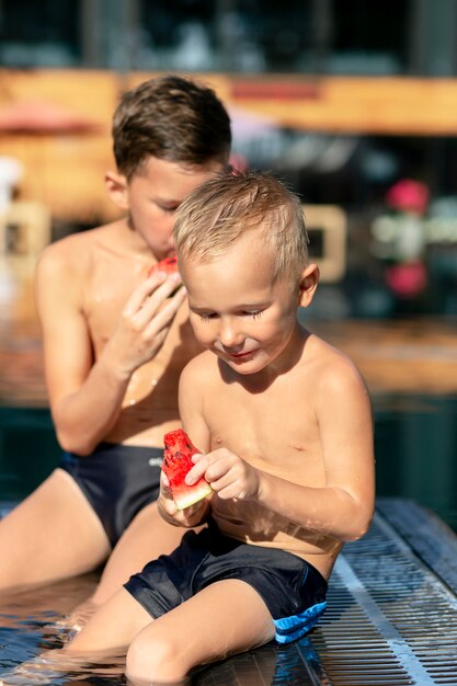 Meninos na piscina com melancia