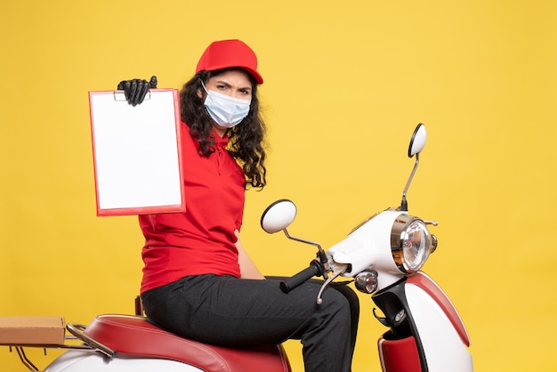 Foto grátis mensageira de frente com máscara segurando nota de arquivo sobre fundo amarelo covid-job uniforme trabalhador serviço pandemia de entrega