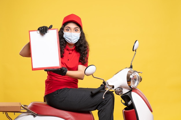 Mensageira de frente com máscara segurando nota de arquivo sobre fundo amarelo covid-job uniforme trabalhador trabalho pandemia entrega