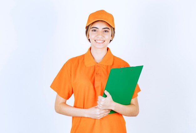 Mensageira de uniforme laranja segurando uma lista de clientes verdes