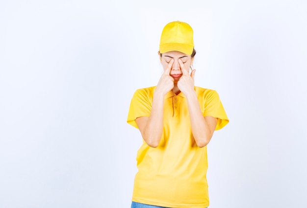 Mensageira feminina em uniforme amarelo parece cansada e com sono.