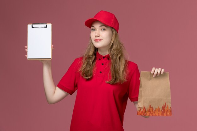 mensageira feminina em uniforme vermelho segurando um pacote de comida junto com um bloco de notas rosa claro