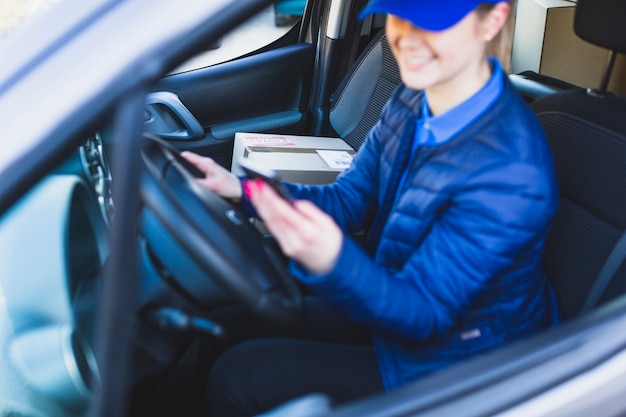 Mensageiro feminino usando o telefone no carro