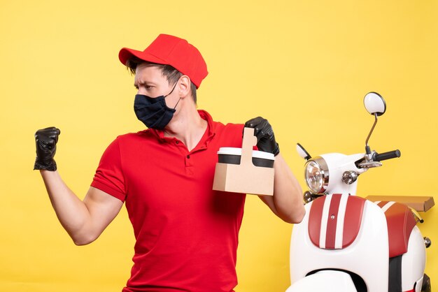 Mensageiro masculino com máscara preta e xícaras de café em um serviço de trabalho uniforme pandêmico de entrega de vírus de trabalho amarelo