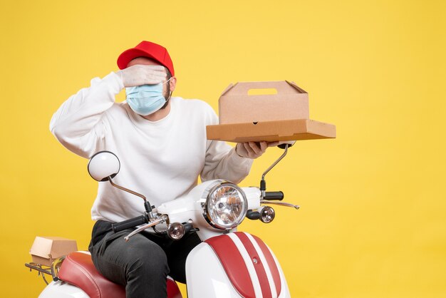 Mensageiro masculino com máscara segurando entrega de comida em amarelo