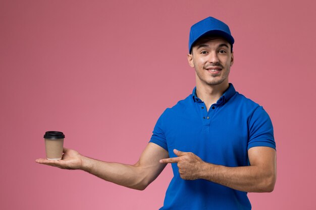 Foto grátis mensageiro masculino de uniforme azul segurando a xícara de café de entrega rosa