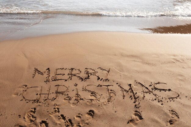 Mensagem de feliz natal de alto ângulo na areia