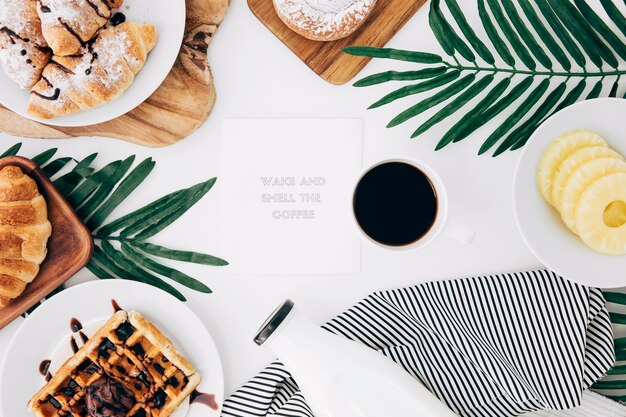 Mensagem no bloco de notas cercado com café da manhã assado; fatias de café e abacaxi na mesa branca