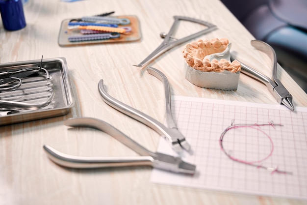 Mesa com amarras de ligadura de instrumentos ortodônticos e modelo de dentes