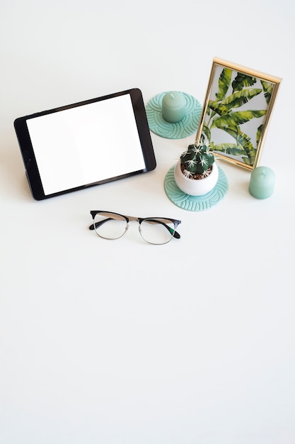 Foto grátis mesa com tablet perto de moldura, planta de casa e óculos