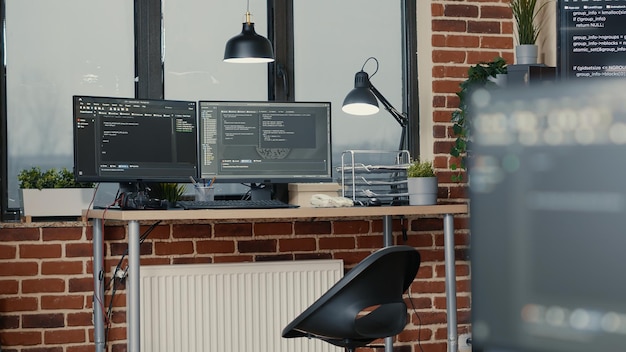 Mesa com vários monitores de computador exibindo código de análise e compilação de linguagem de programação no escritório vazio da agência de desenvolvimento de software. Servidores de computação em nuvem algoritmos de big data.