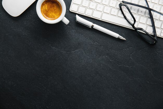 Mesa de escritório com café, teclado e bloco de notas