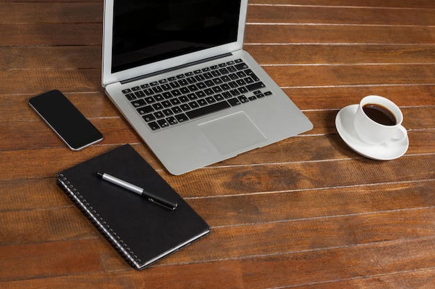 mesa de escritório com computador portátil, bloco de notas e chávena de café