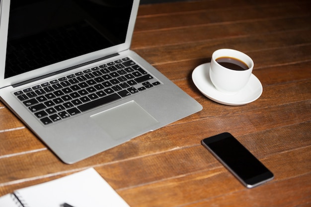 mesa de escritório com computador portátil, telemóvel e chávena de café