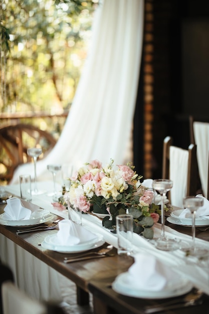 Mesa de jantar com peça central floral na recepção do casamento.