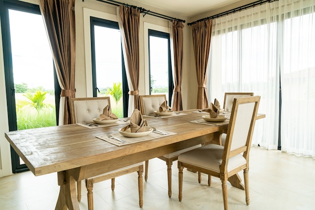 Mesa de jantar de madeira em uma sala com cortina e janela