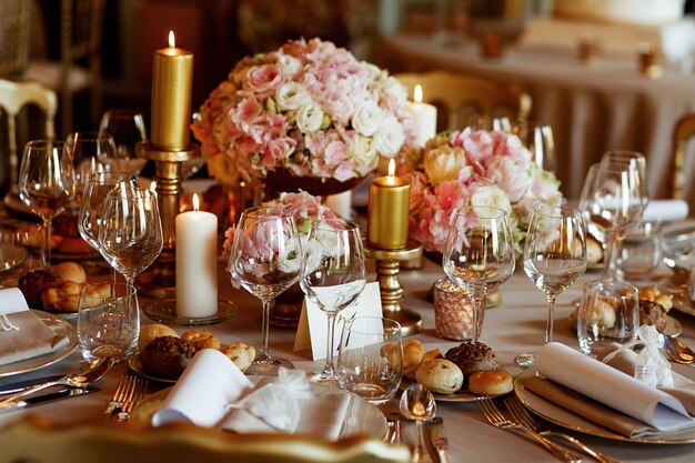 Mesa de jantar rica servida em tons rosa e dourados