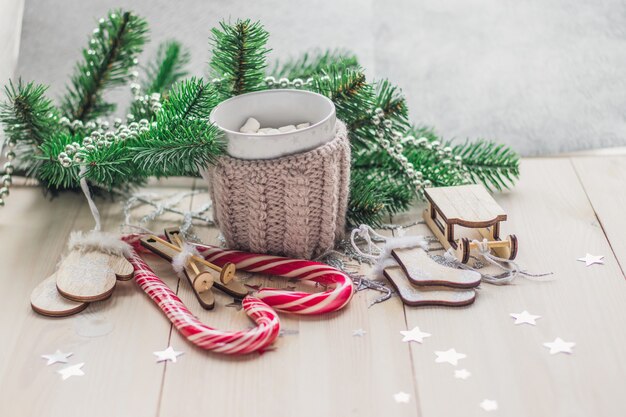 Mesa de madeira coberta com marshmallows de bastões de doces e decorações de Natal sob as luzes