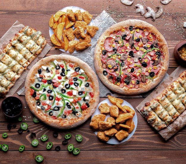 Mesa de madeira com pizzas e lanches nele