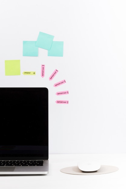 Mesa de trabalho minimalista arranjada com laptop e notas na parede