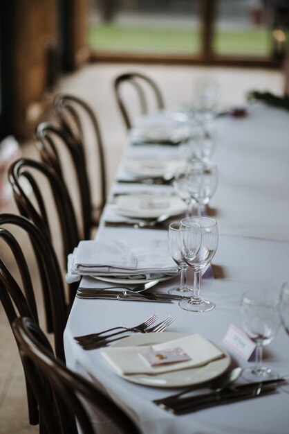 Mesa decorada para o dia do casamento com pratos, guardanapos, taças de vinho, garfos e facas