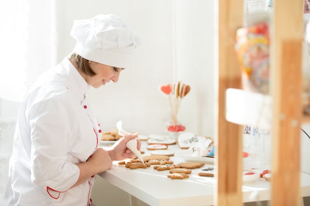 Mesclador feminino profissional sentado e decorando um gengibre