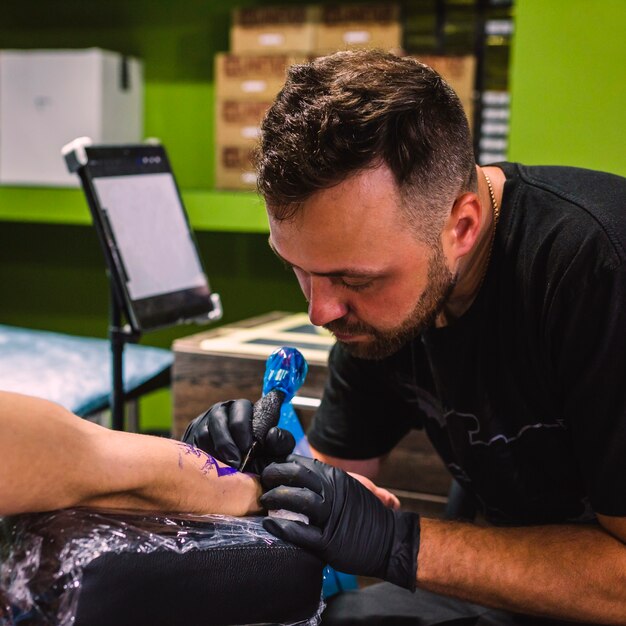 Mestre fazendo tatuagem com máquina de agulha