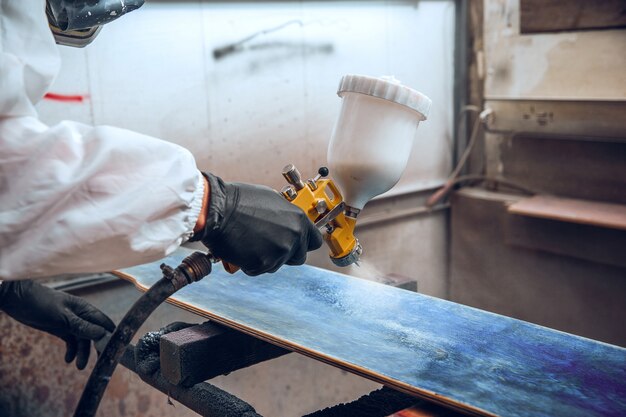 Mestre pintor em fábrica - pintura industrial em madeira com pistola.