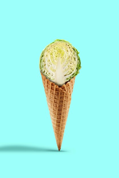 Metade de um repolho cru em um cone de bolacha contra um fundo turquesa. Conceito de nutrição saudável, alimentos e colheita de legumes sazonais. Feche, copie o espaço