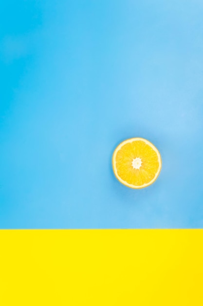 Metade de uma laranja em um plano de fundo azul e amarelo minimalista