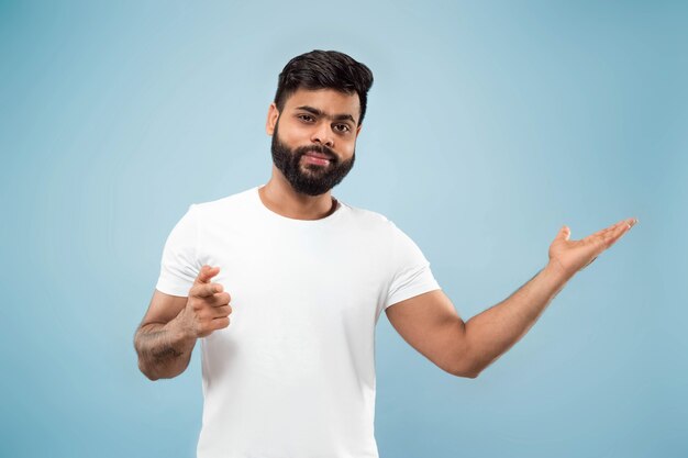 Metade do comprimento fechar o retrato de um jovem hindu em uma camisa branca sobre azul.